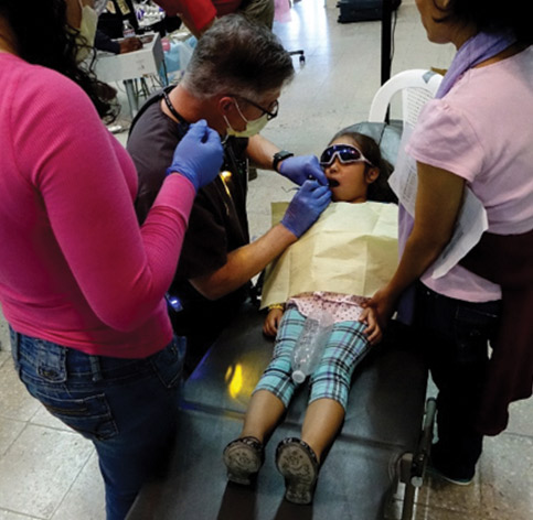 Dentists treating young girl at clinic